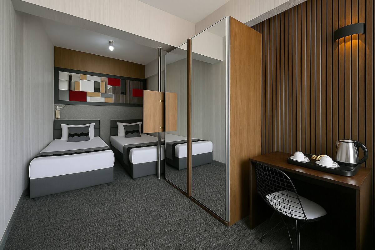 A hotel room with two single beds, a desk with a chair, a coffee maker, and a mirror.