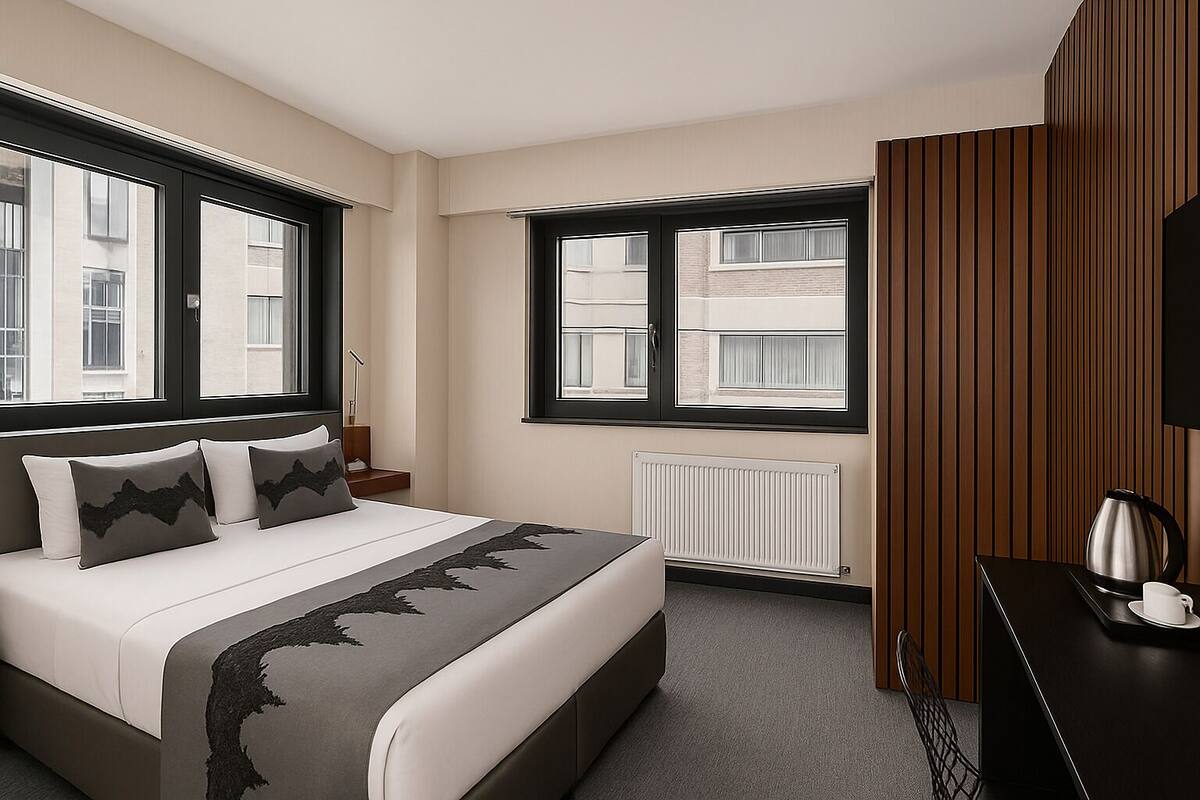 A modern hotel room with a large bed, a wooden panel wall, a radiator, and a view of the city through large windows.