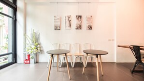 A modern interior with two round tables, white chairs, and a wall-mounted art display. - Herman Hostel (Liuqiu)