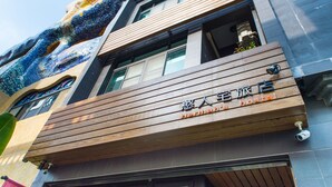 A hotel facade with a wooden overhang and signage in a foreign language. - Herman Hostel (Liuqiu)
