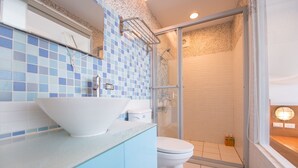 A bathroom with a white sink, blue tiles, a glass shower enclosure, and a toilet. - Herman Hostel (Liuqiu)