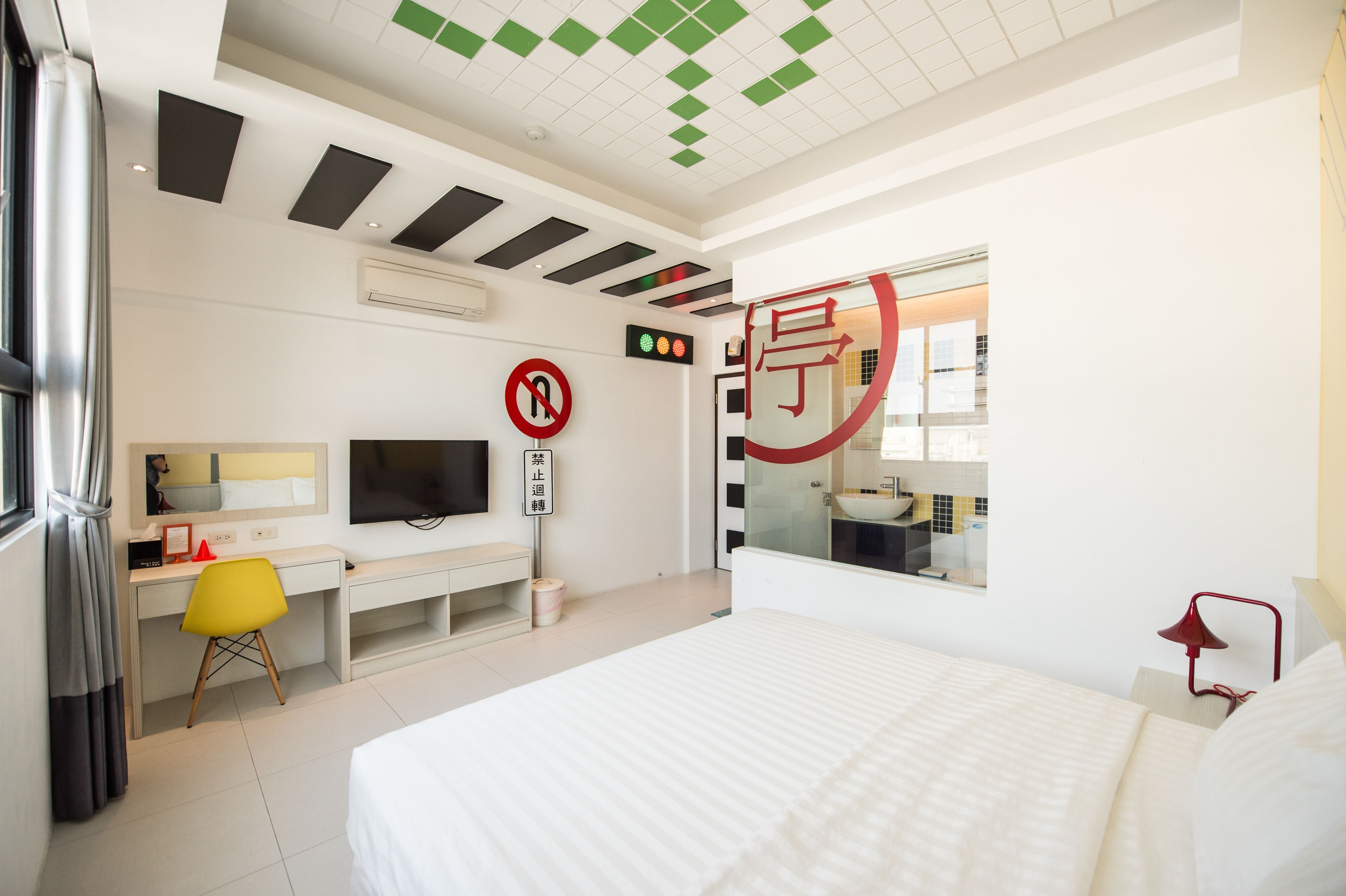 Una habitación de hotel moderna con cama, escritorio, silla, televisor, espejo y ventana.