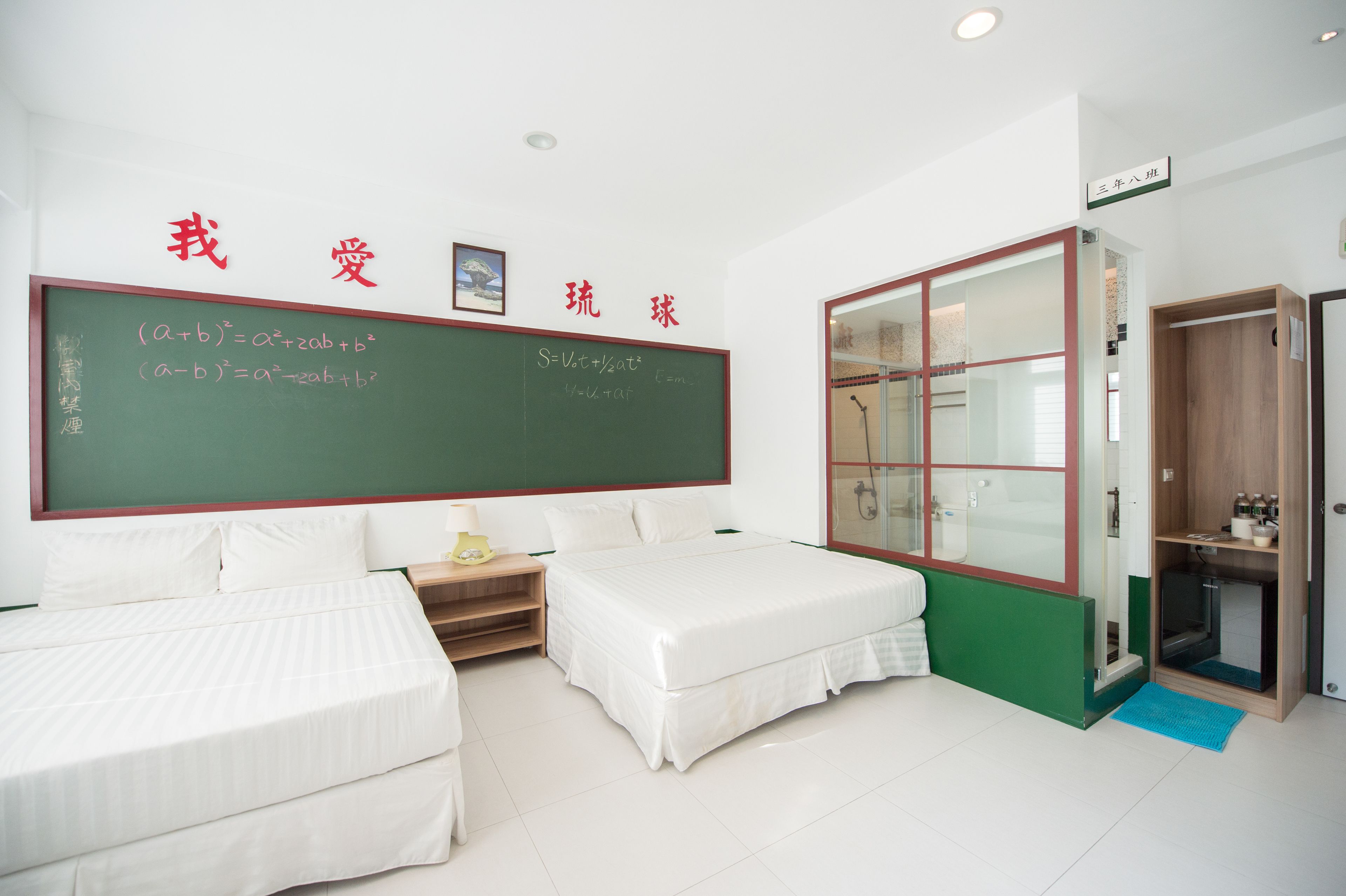 Una habitación de hotel con una cama, un escritorio pequeño, una estantería y un ventanal grande.