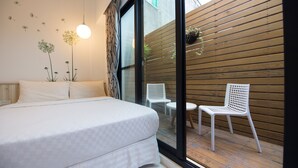 A bedroom with a large bed, a white chair, and a small table. - Herman Hostel (Liuqiu)