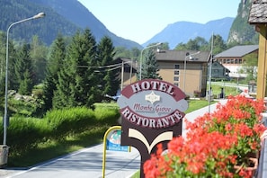 A hotel sign with 'HOTEL Monte Giove RISTORANTE' written on it, surrounded by greenery and mountains. - Hotel Monte Giove (Premia)