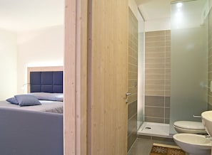 A bedroom with a bed, a nightstand, and a bathroom with a shower, toilet, and sink. - Hotel Monte Giove (Premia)