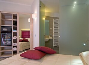 Una habitación de hotel con cama, armario, baño con toallero y zona de ducha.