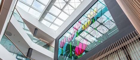 A multi-level atrium with glass railings and a central stained glass artwork.