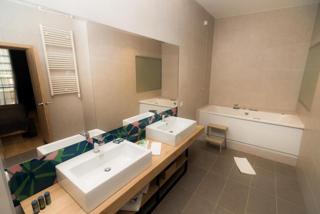 A modern bathroom with two sinks, a large mirror, and a shower area.