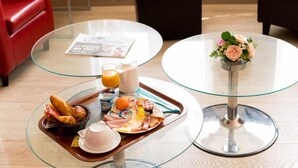 A breakfast tray with croissants, eggs, and beverages on a glass table. - Allotel (Fos-sur-Mer)