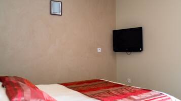 Habitación de hotel con una cama, un televisor en la pared y una pequeña foto en el marco.