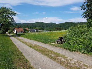 Un sentiero lastricato con una panchina, case e un paesaggio collinare sullo sfondo.