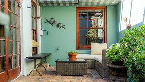 A cozy outdoor seating area with wicker furniture, a wooden bench, and a potted plant. - Vesperdene Mews 2 (Cape Town)
