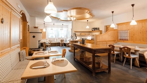 Un restaurant chaleureux, décoré de bois, avec de nombreuses tables et des lampes suspendues.