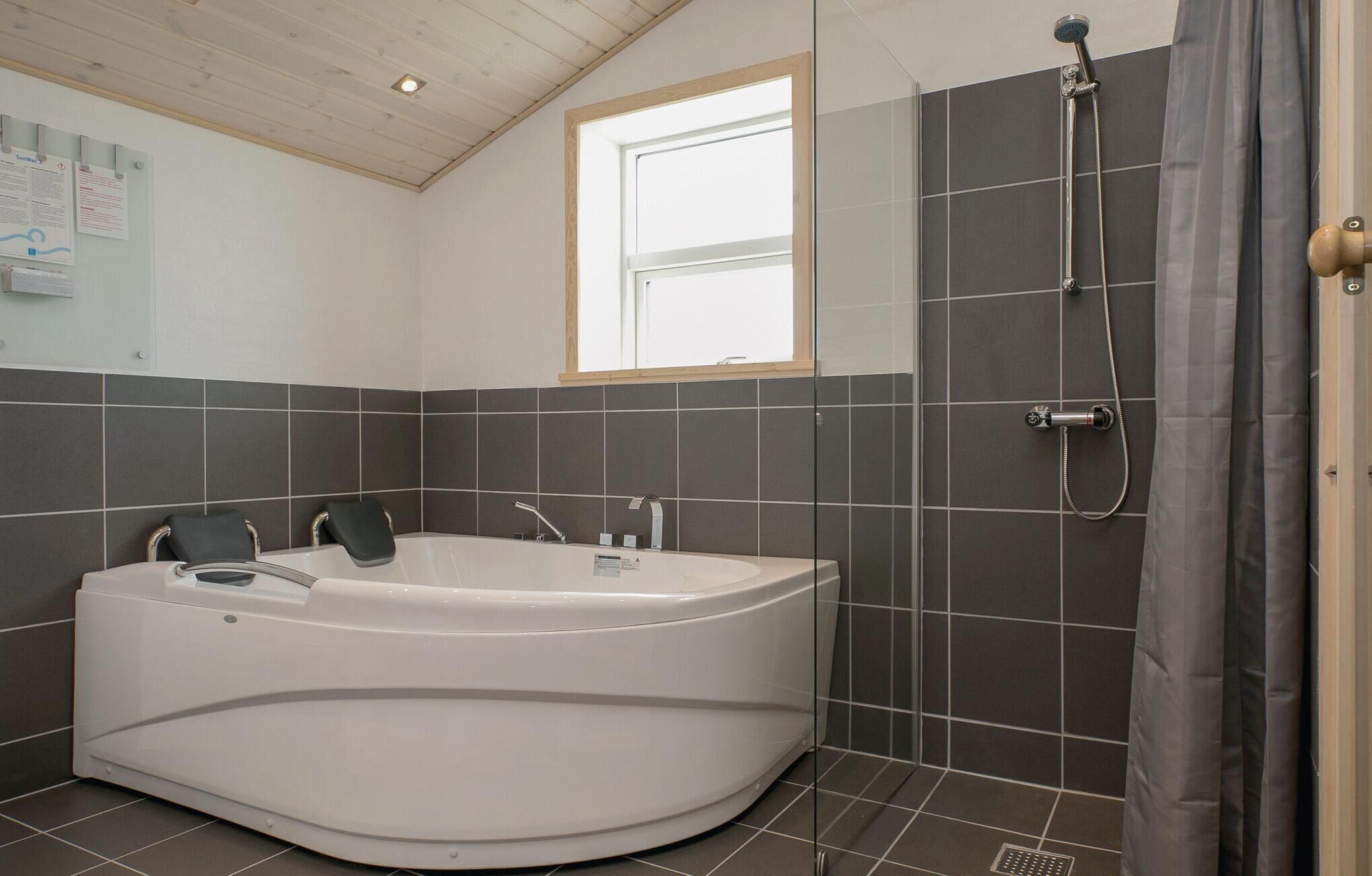 Ein modernes Badezimmer mit einer freistehenden Badewanne, einer Dusche und einem Fenster, das für natürliches Licht sorgt.
