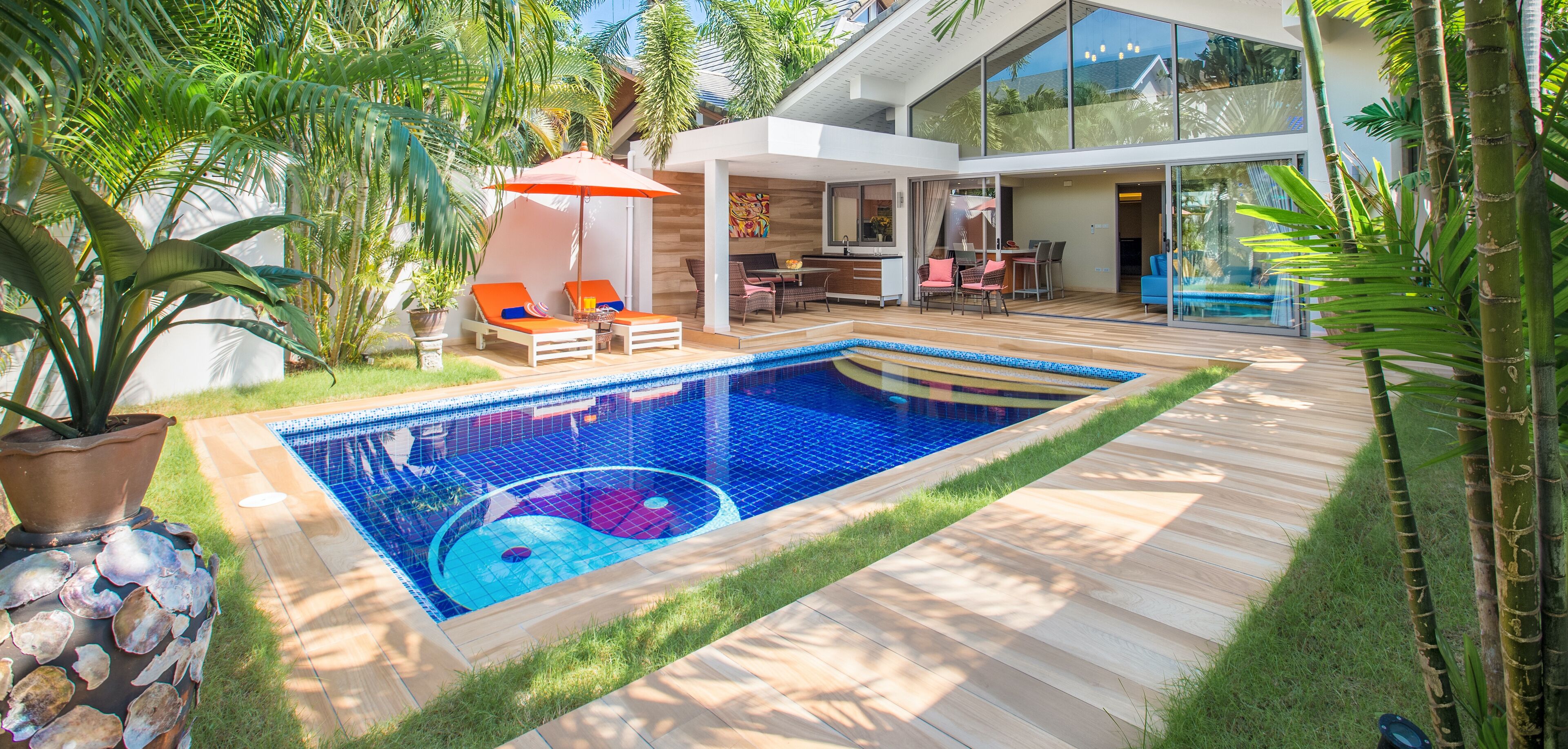 A modern house with a swimming pool, outdoor seating, and lush greenery.