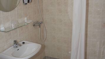 A bathroom with a sink, mirror, shower, and toilet.