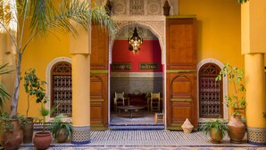 An entrance with a tiled floor, wooden doors, and a hanging light fixture. - Medina Social Club - Riad (Fes)
