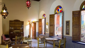 A traditional room with a checkered floor, wooden furniture, a round table, and a bookshelf. - Medina Social Club - Riad (Fes)