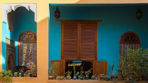 A traditional building with wooden shutters, a blue facade, and multiple potted plants. - Medina Social Club - Riad (Fes)