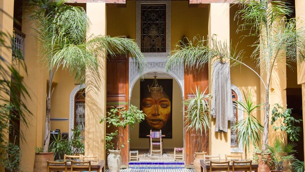 An interior courtyard with a tiled floor, wooden furniture, and potted plants. - Medina Social Club - Riad (Fes)