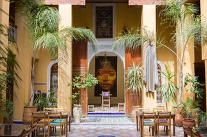 An interior courtyard with a tiled floor, wooden furniture, and potted plants. - Medina Social Club - Riad (Fes)
