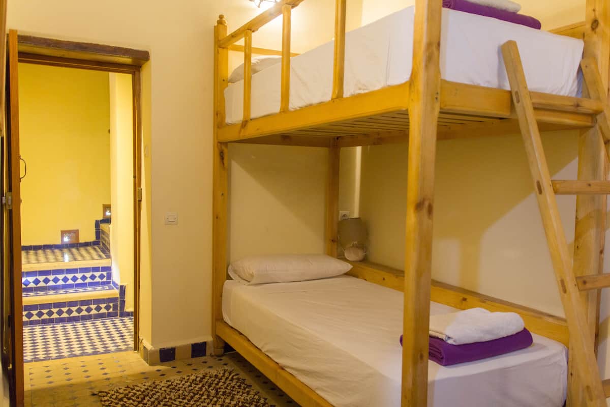 Dormitorio con literas, una pequeña mesita de noche y suelo estampado.
