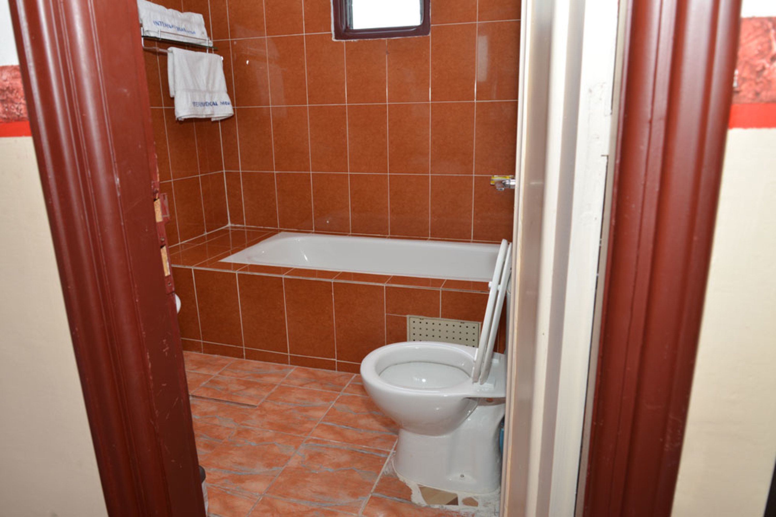 A bathroom with a bathtub, toilet, and tiled floor.