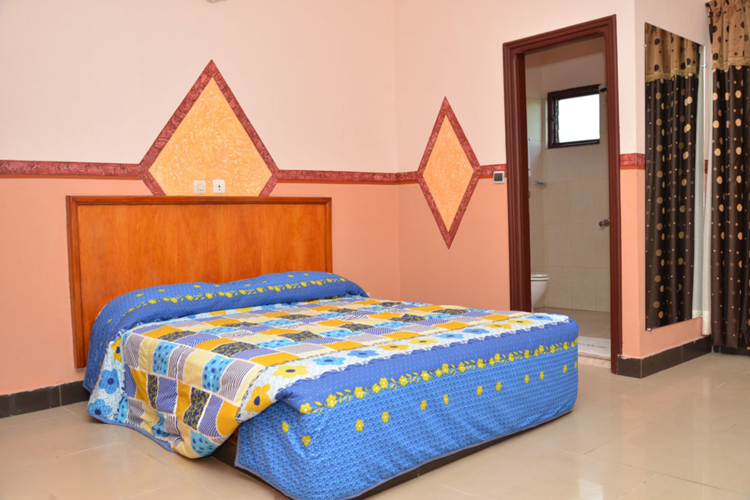 Een slaapkamer met een bed, een houten hoofdbord, een deur en een zichtbare badkamer door een open deur.