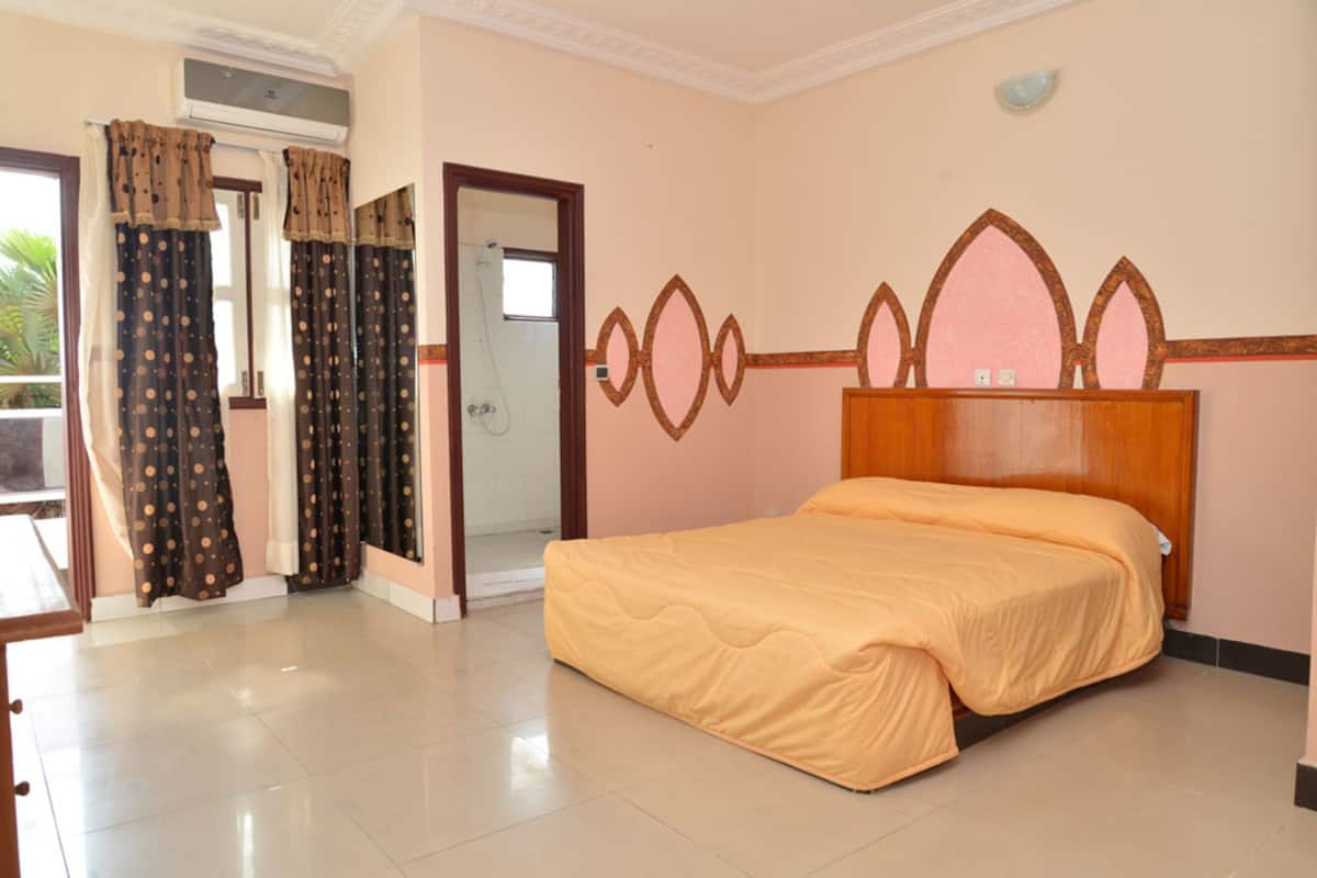A bedroom with a bed, curtains, and a door leading to a balcony.