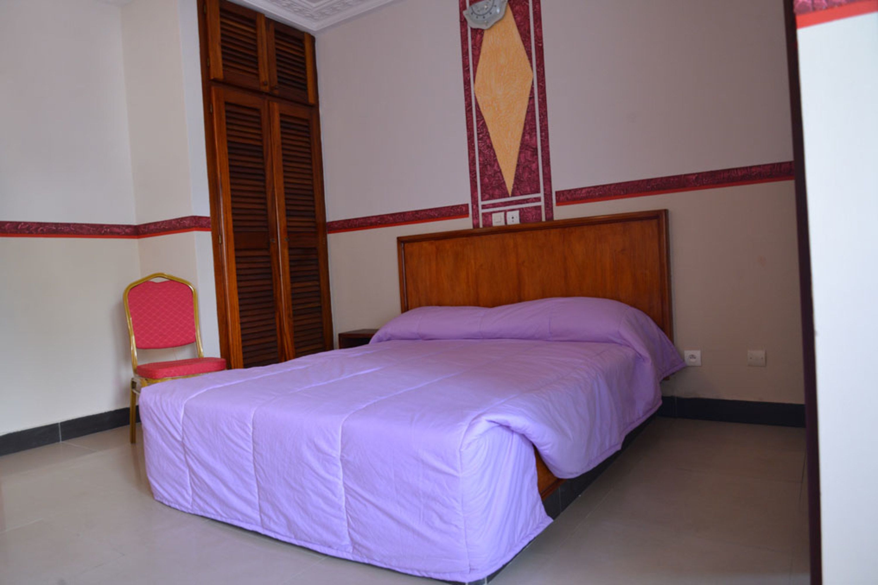 A bedroom with a bed, a chair, and a wardrobe.