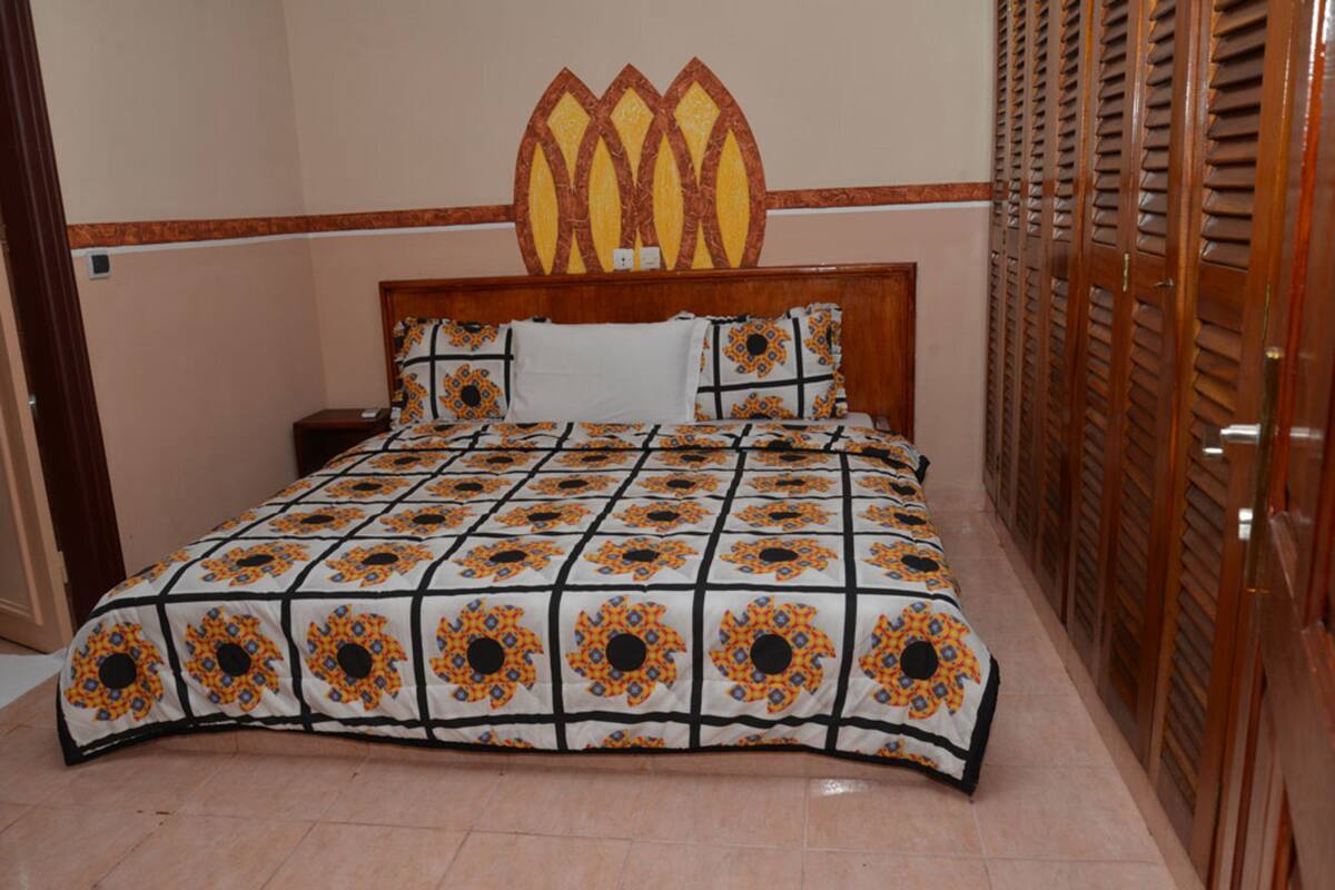 A bedroom with a bed, a headboard, a nightstand, and a wooden door with louvered panels.