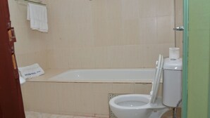 Une salle de bain équipée d’une baignoire, de toilettes et d’un porte-serviettes avec une serviette blanche.