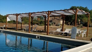 A swimming pool with sun loungers and a pergola structure. - Agriturismo Il Casalino (Civitella Paganico)