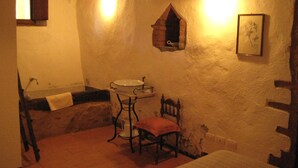 A rustic bathroom with a sink, chair, and a small window. - Agriturismo Il Casalino (Civitella Paganico)