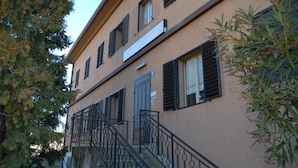 A two-story building with a staircase and black metal railings. - Locanda Gaia (Muggia)