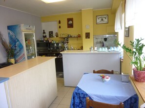 A compact kitchen with a central island, a dining area with a table, and a refrigerator.