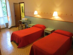 A hotel room with two single beds, a desk with a chair, a small table, and two bedside lamps.