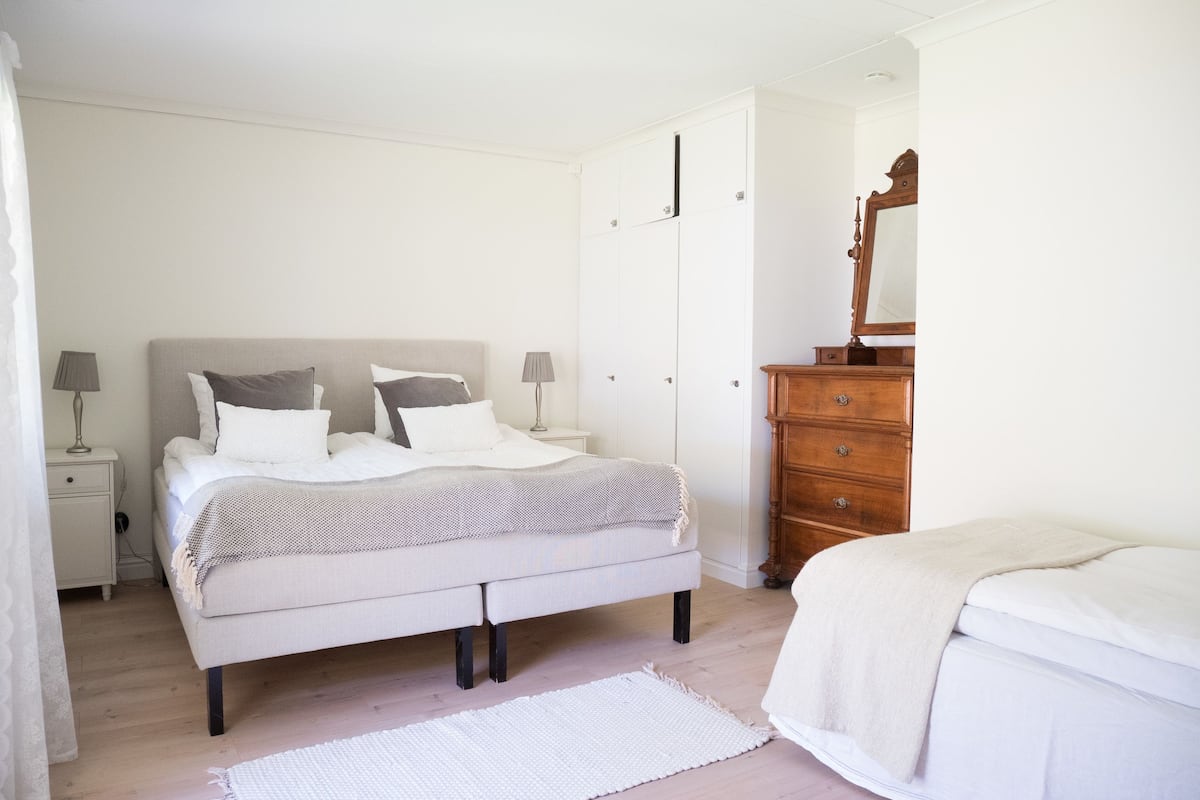 A bedroom with a bed, nightstands, a dresser, and a mirror.