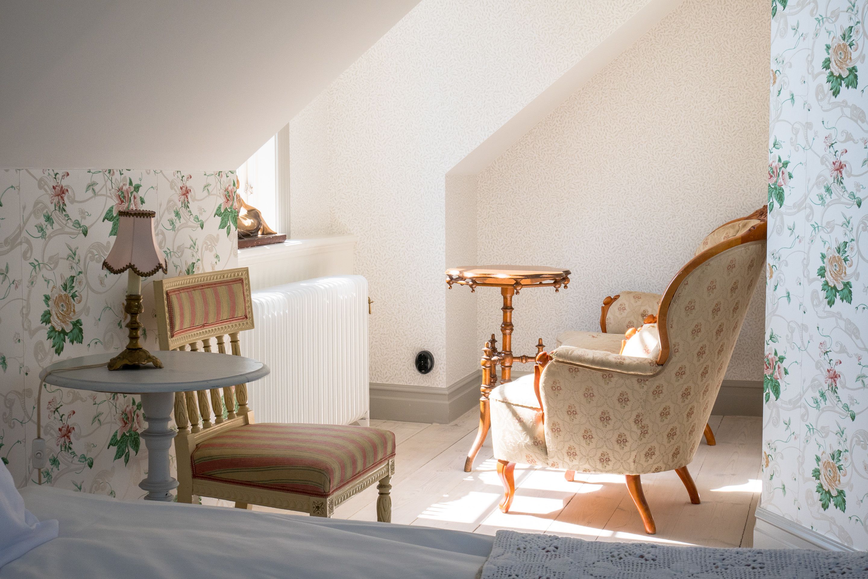 A room with a bed, a chair, a table, and a radiator.