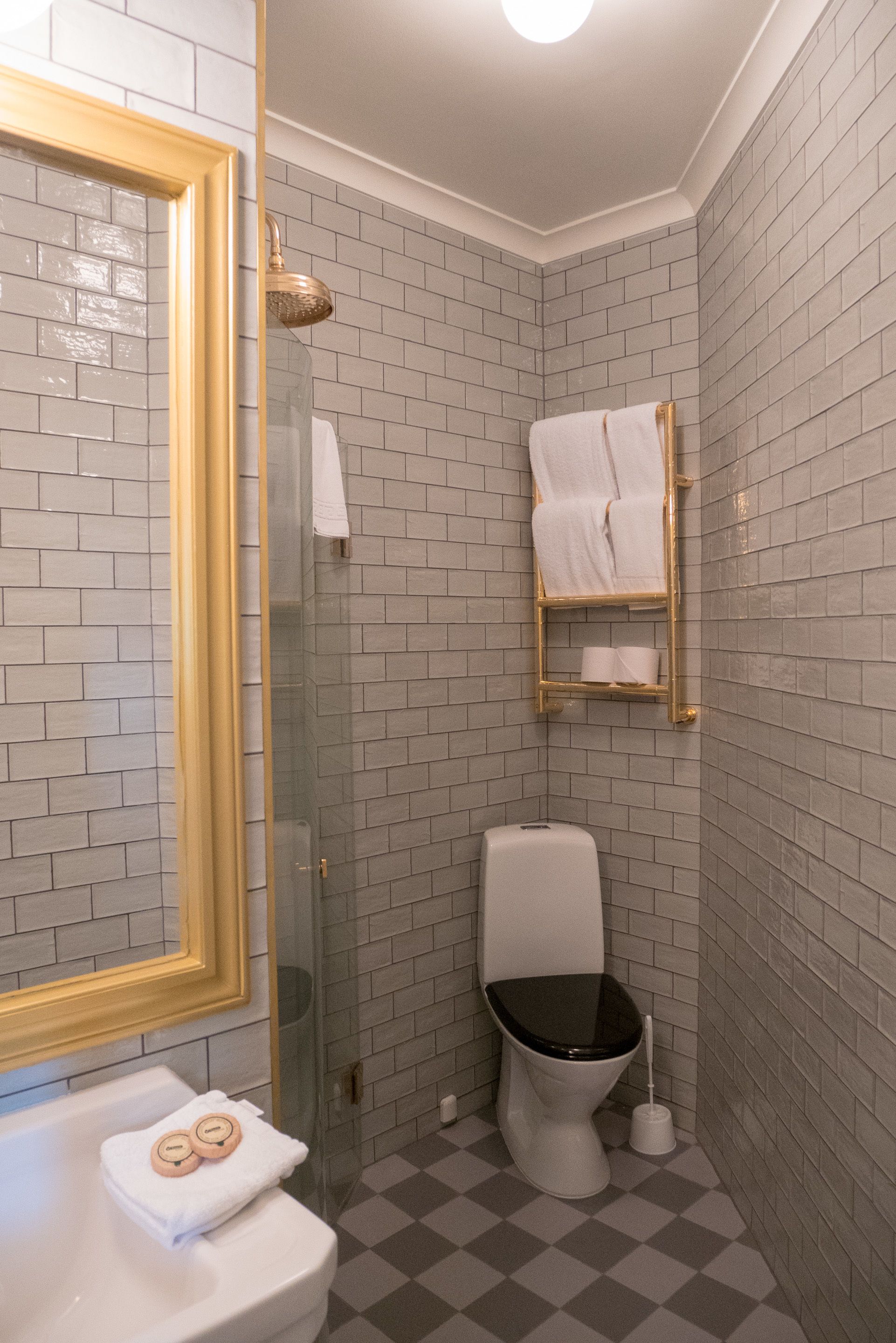 Un baño con inodoro, cabina de ducha de vidrio, lavamanos con espejo y toallero.