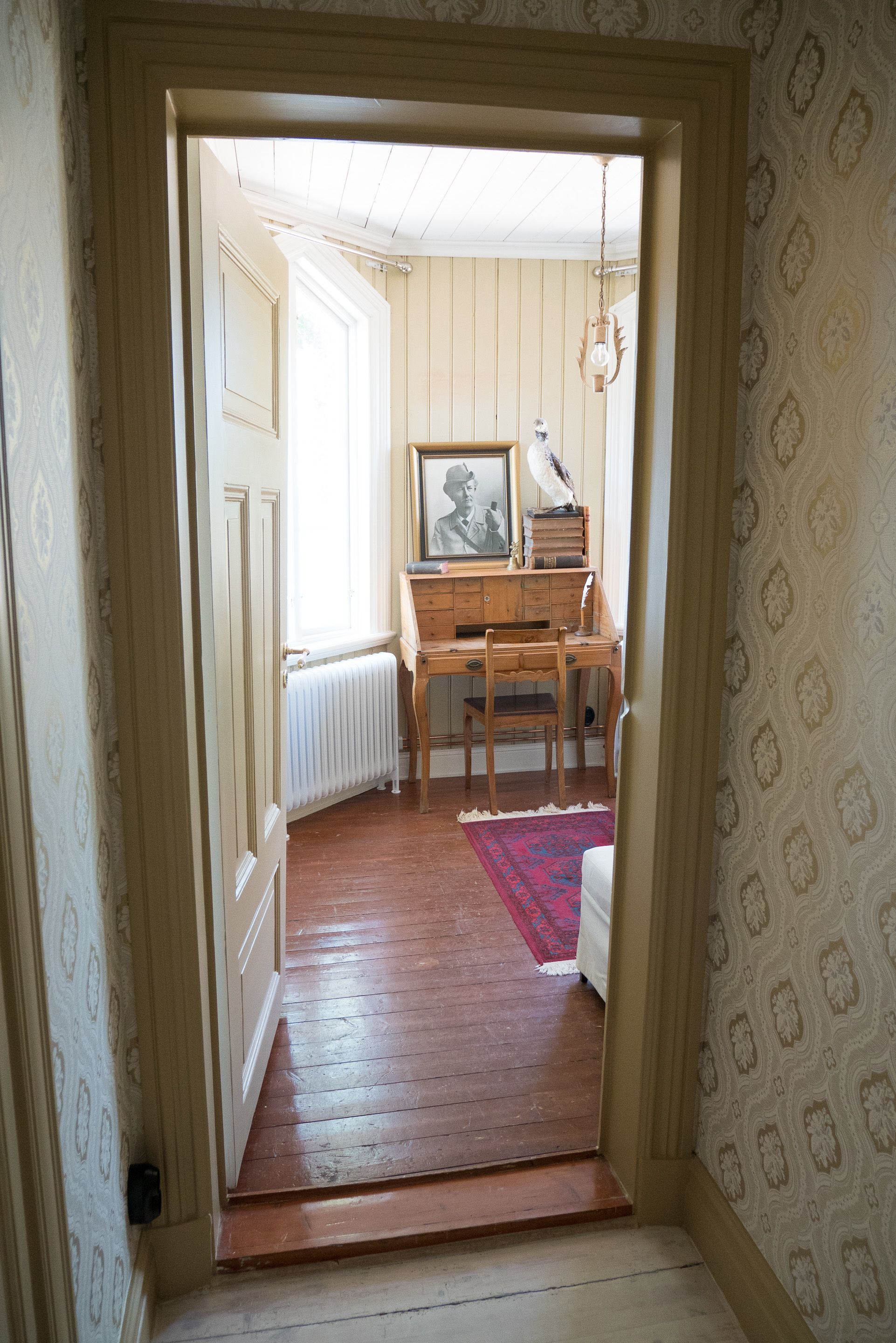 Habitació amb escriptori de fusta, radiador i paper tapet.