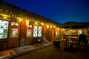 A traditional building with wooden doors and windows, a brick exterior, and outdoor seating area with tables and chairs. - Hongxingju Inn (Jinzhong)