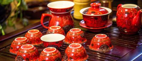 Um conjunto de chá tradicional com várias chávenas e um bule sobre uma mesa de madeira.