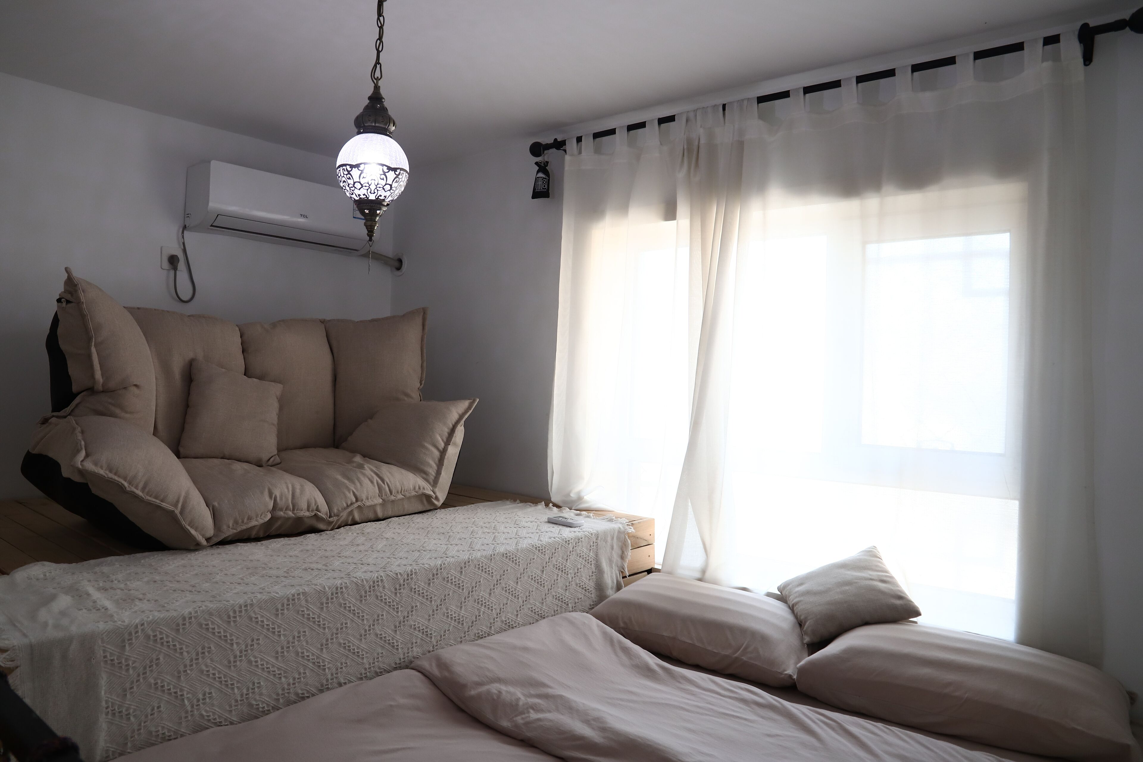 A bedroom with a bed, a sofa, and a window with curtains.