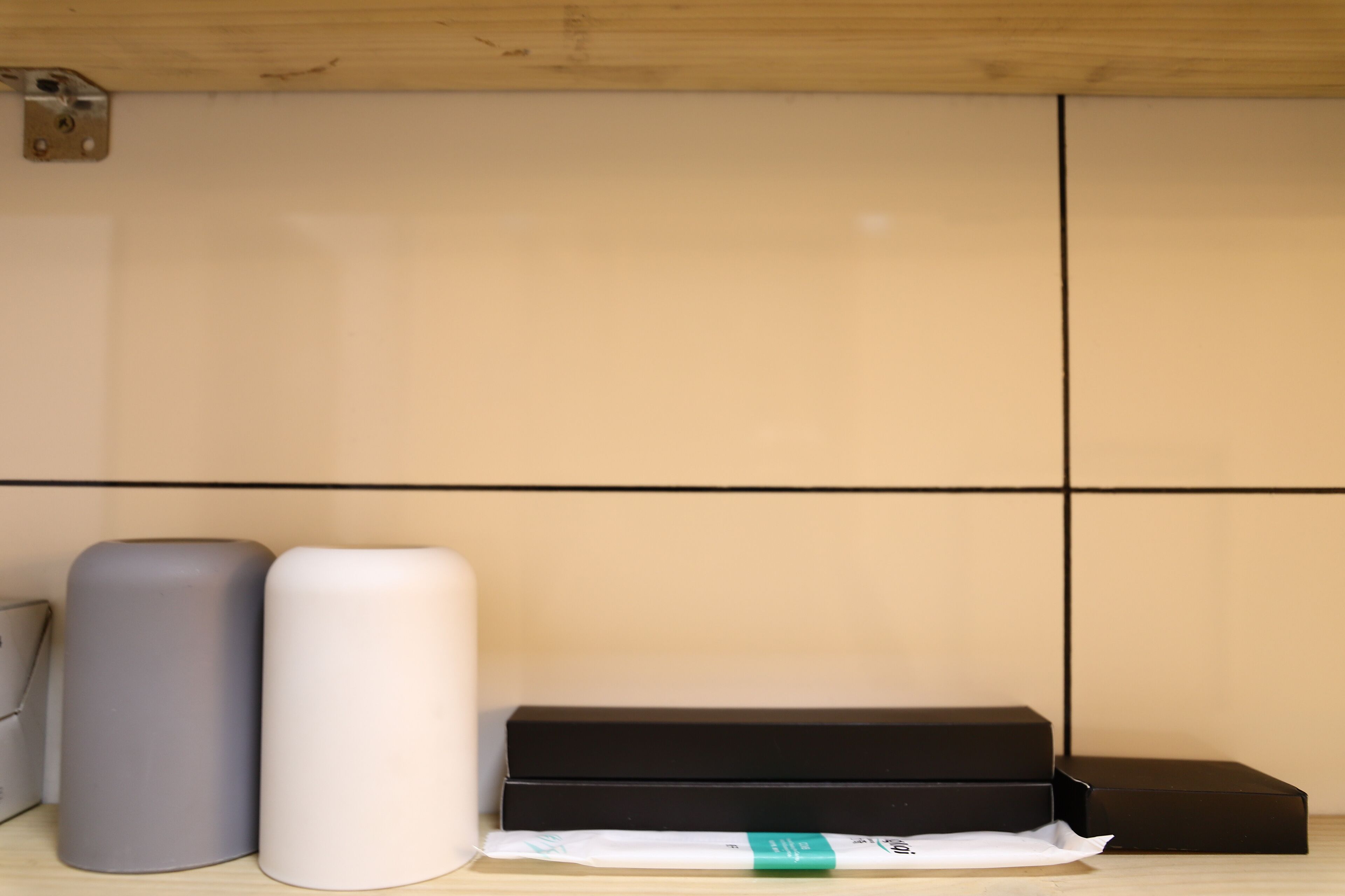 A room with a wooden ceiling, a tiled wall, and a black box on the floor.
