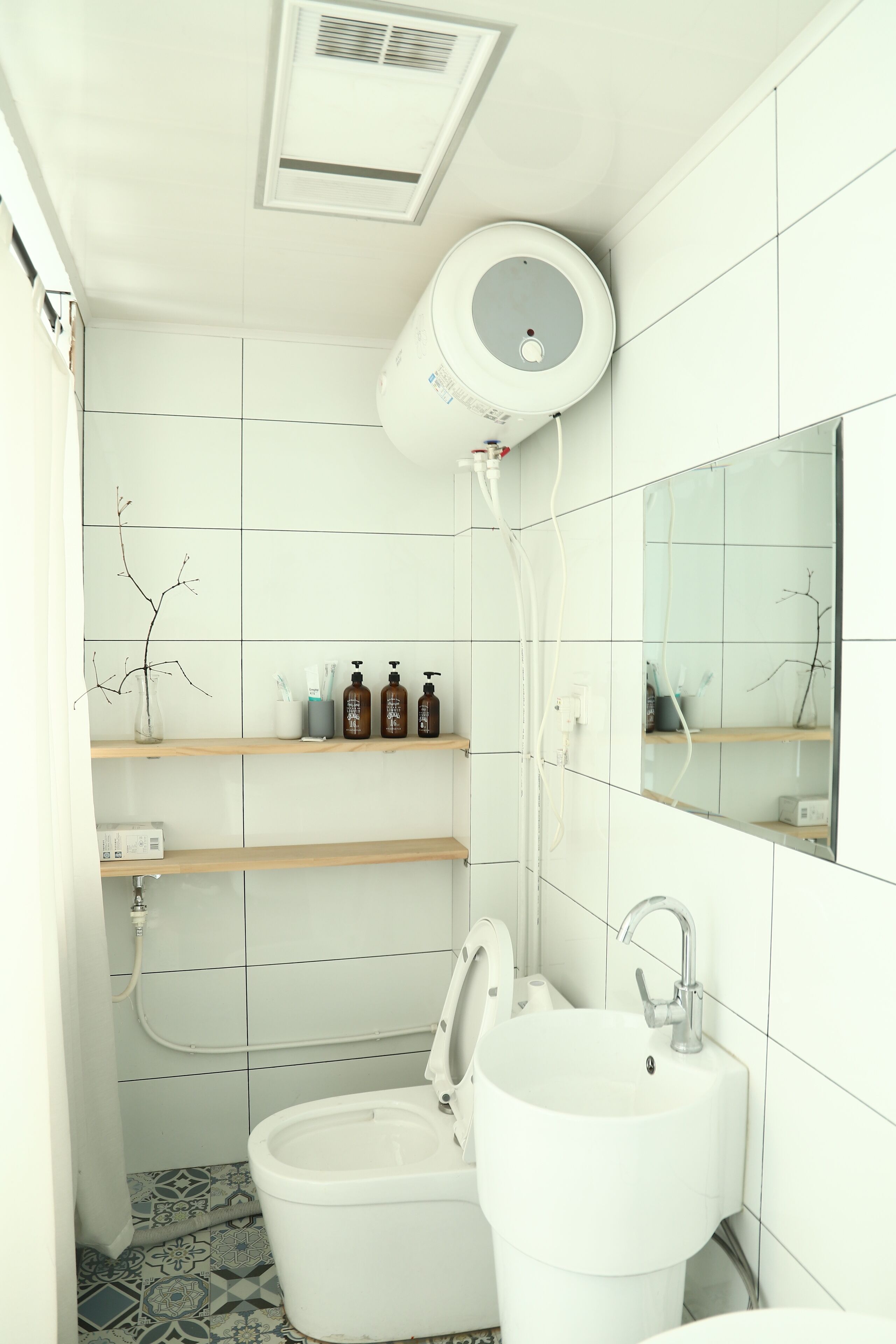 A bathroom with a toilet, sink, and shelves with toiletries.