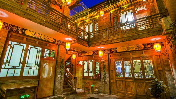 Un bâtiment traditionnel doté de balcons en bois richement décorés, de nombreuses fenêtres aux motifs complexes et de lanternes suspendues.