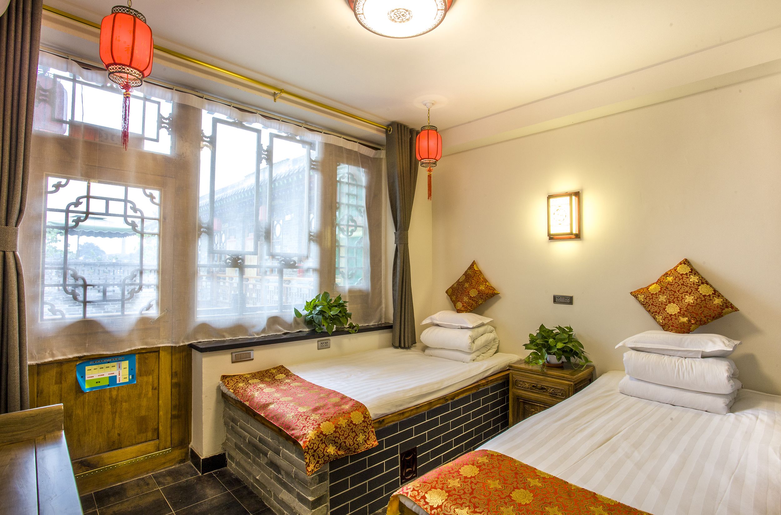 Una habitación tradicional con cama, una mesita y una ventana con cortinas.