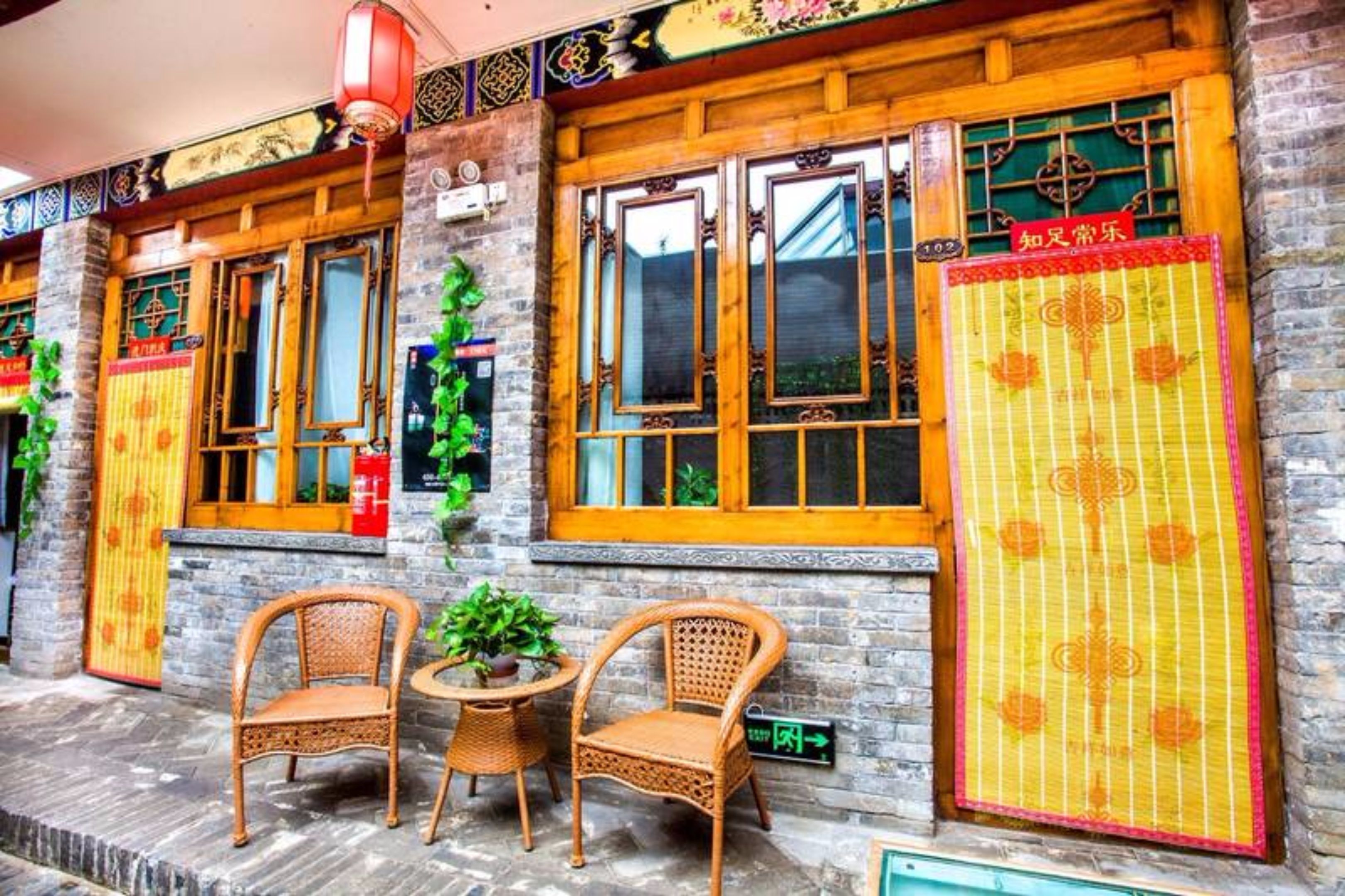 A traditional building with wooden windows and doors, two wicker chairs, and a small table with a plant.